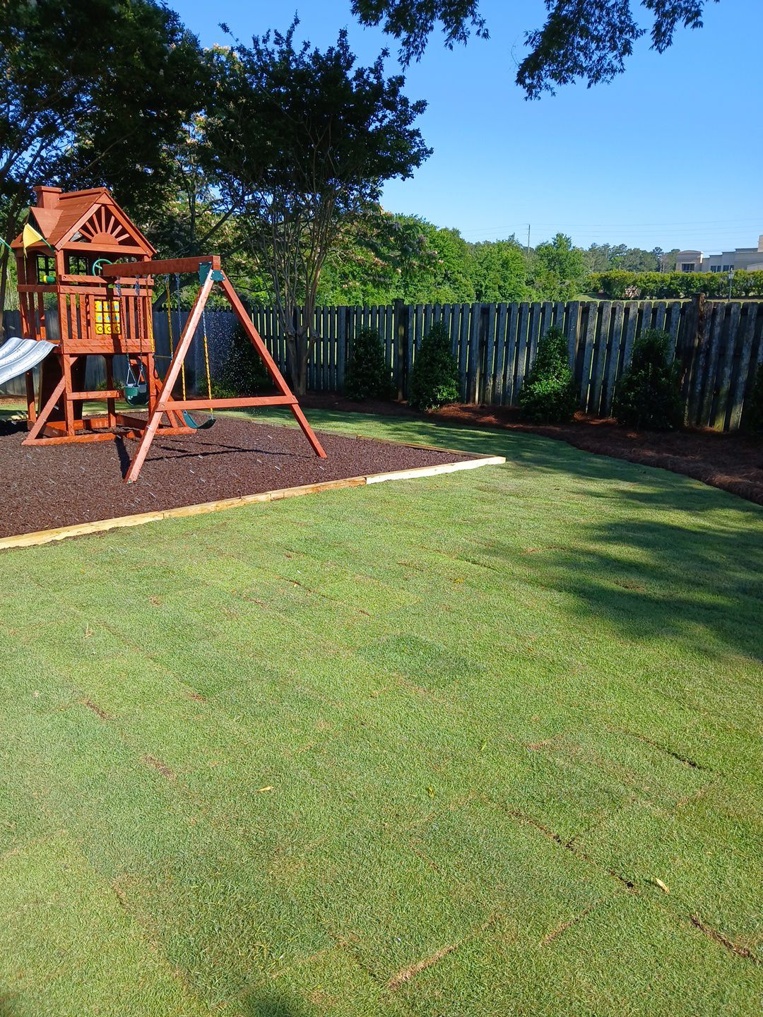 A finished BTOP backyard — fresh sod lawn with a play set